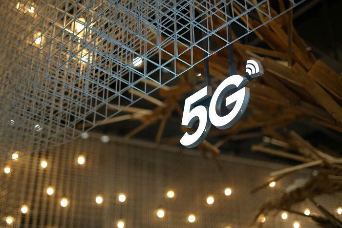 5G sign illuminated against a backdrop of metal grid and lights, symbolizing modern technology amidst conspiracy theory discussions.