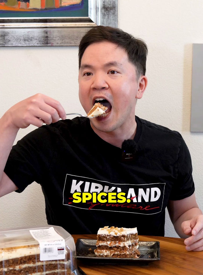 Man eating carrot cake with "Kirkland Signature" shirt, debating hidden ingredient in Costco dessert.