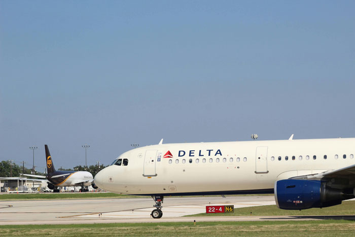 Delta airplane taxiing on runway under clear sky, representing airlines in travel context. Delta airplane taxiing on runway under clear sky, representing airlines in travel context.