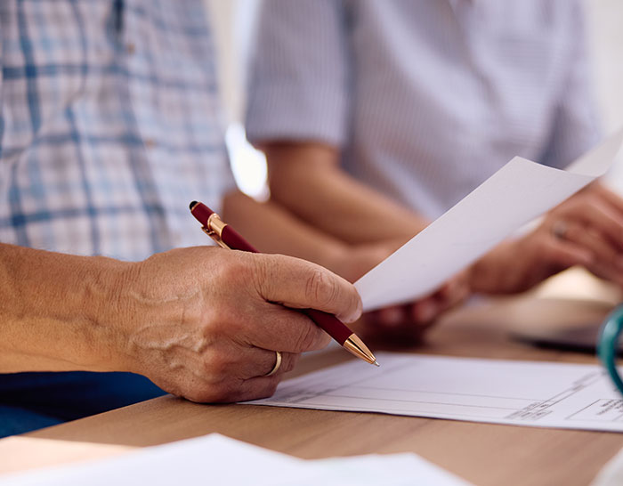 A person reading documents at a desk, focusing on family inheritance issues. A person reading documents at a desk, focusing on family inheritance issues.