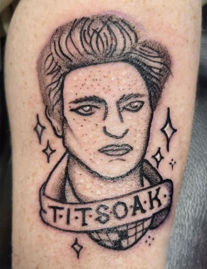 Bad tattoo of a portrait with humorous banner text on skin.