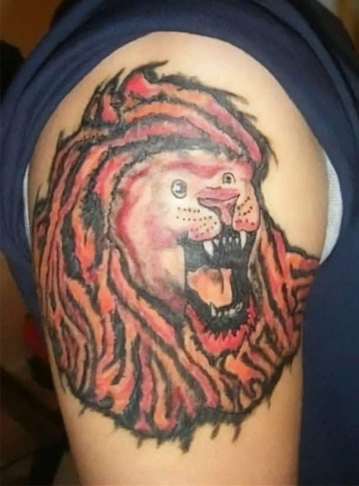 Bad tattoo of a lion with distorted features on an arm, showcased humorously.