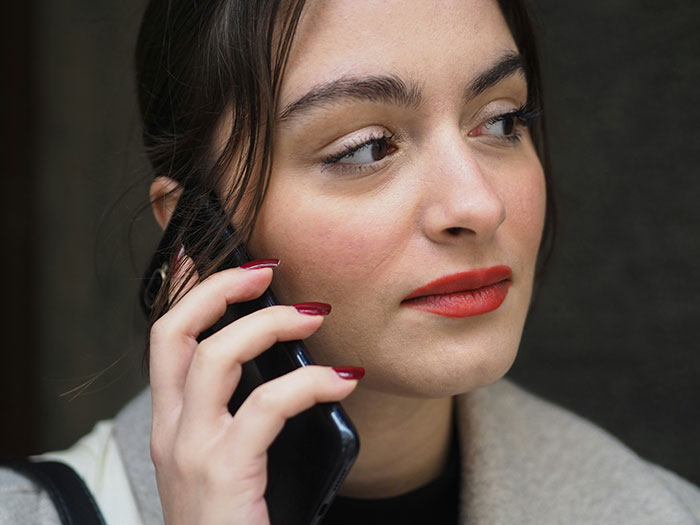 Woman on phone, appearing tense, wearing a coat.