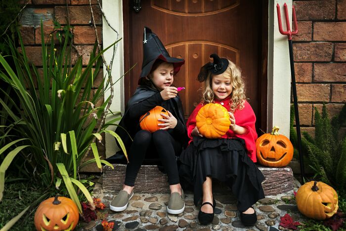 Children in Halloween costumes holding pumpkins, showcasing American traditions.