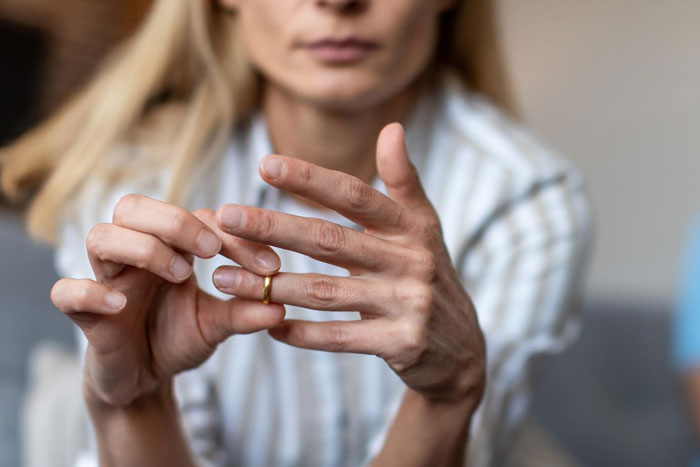 Woman removing wedding ring, symbolizing threat of divorce after dad defends bi daughter and family conflict over lifestyle. Woman removing wedding ring, symbolizing threat of divorce after dad defends bi daughter and family conflict over lifestyle.