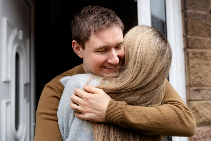 Man hugging woman at doorway, representing family conflict over dad defending bi daughter, causing wife to threaten divorce. Man hugging woman at doorway, representing family conflict over dad defending bi daughter, causing wife to threaten divorce.