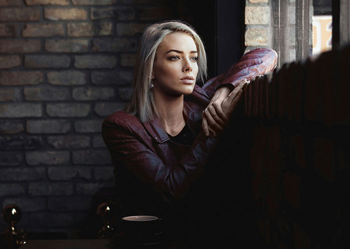 Woman with blonde hair and maroon jacket gazing out of a window, contemplating life changes and finding personal space. Woman with blonde hair and maroon jacket gazing out of a window, contemplating life changes and finding personal space.