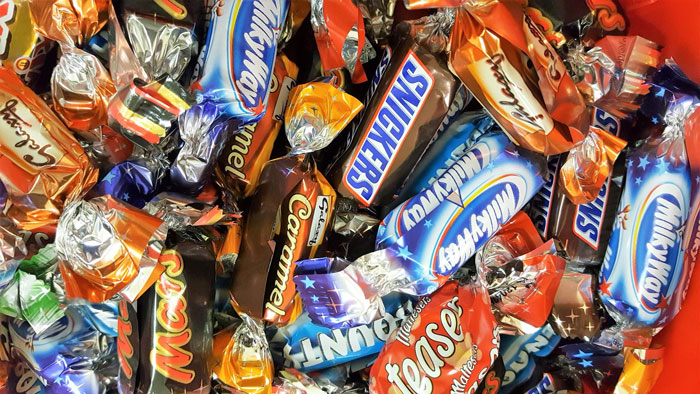 Assorted candy bars in colorful wrappers filling a pantry bowl. Assorted candy bars in colorful wrappers filling a pantry bowl.
