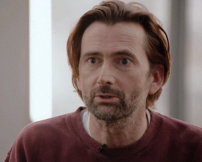 Man in a maroon sweater speaking, related to David Tennant and trans allyship discussion.