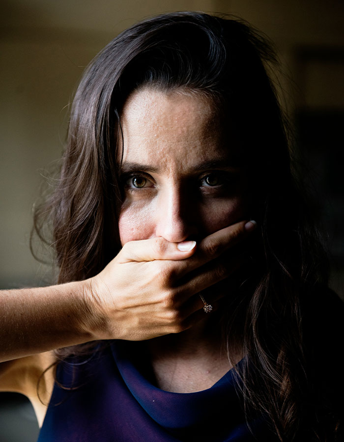 Woman covers mouth, symbolizing a plea, linked to a "hero" delivery driver's intervention.