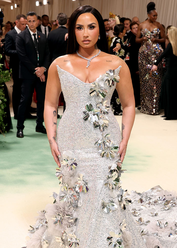 Celebrity in elegant gown at a formal event, showcasing a slim frame amidst a crowd.