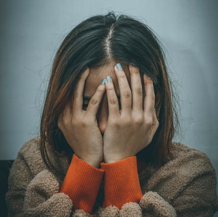 Person covering face with hands, appearing shocked and appalled by something disgusting.