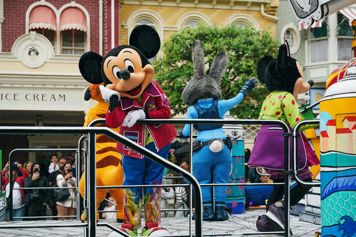 Disney fans rejoice as characters parade in colorful costumes at the park, celebrating new 2025 discounts.