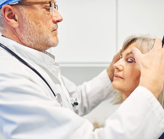 A surgeon assessing a 66-year-old woman's face for plastic surgery. A surgeon assessing a 66-year-old woman's face for plastic surgery.