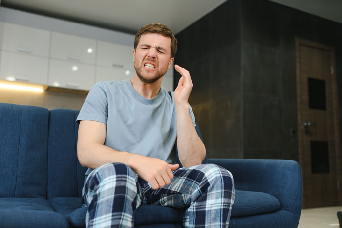 Man on couch in frustration, representing couple conflict over an untrainable rescue dog. Man on couch in frustration, representing couple conflict over an untrainable rescue dog.