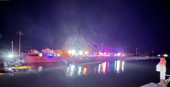 Emergency lights reflected in a canal at night after a crash scene involving a drunk driver.