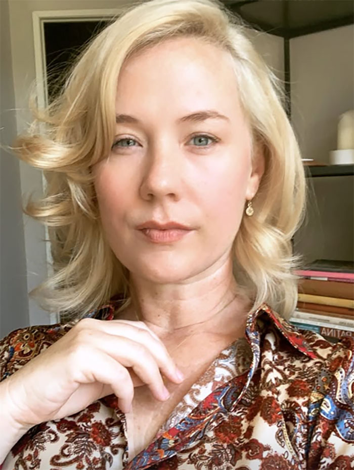 Blond woman in a patterned blouse with books in the background, discussing childhood confusion and deprivation.