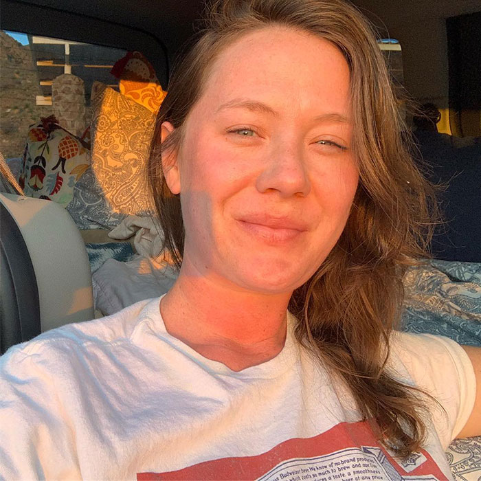 A woman in a white shirt sits in a sunlit space, connected to themes of confusion and deprivation.