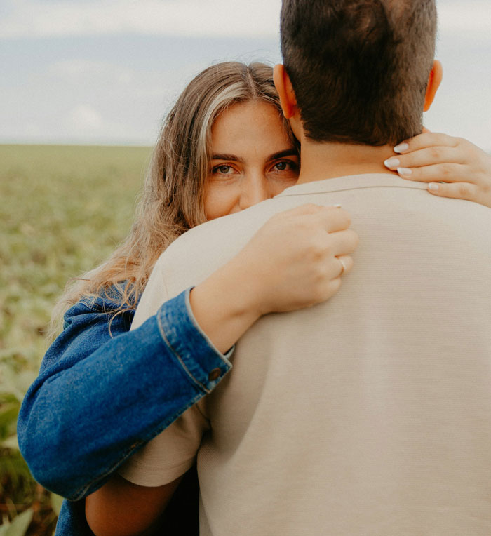 Woman embracing man in a field, conveying emotion and connection amid relationship challenges.