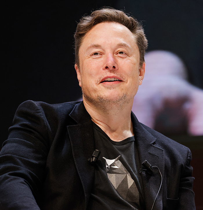 A person in a black jacket speaking at an event.