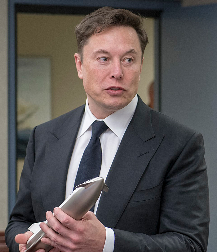 Man in a suit holding a model rocket.