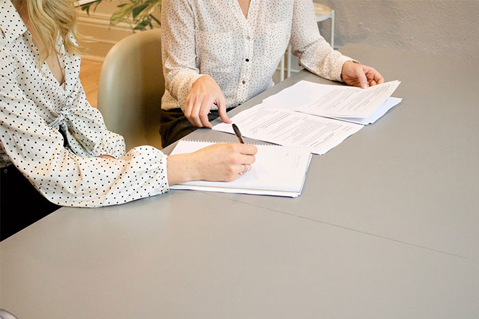 Two people reviewing documents at a table, discussing topics employers prefer their employees don't know.