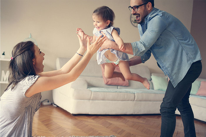A joyful family playing with their child in a cozy living room.