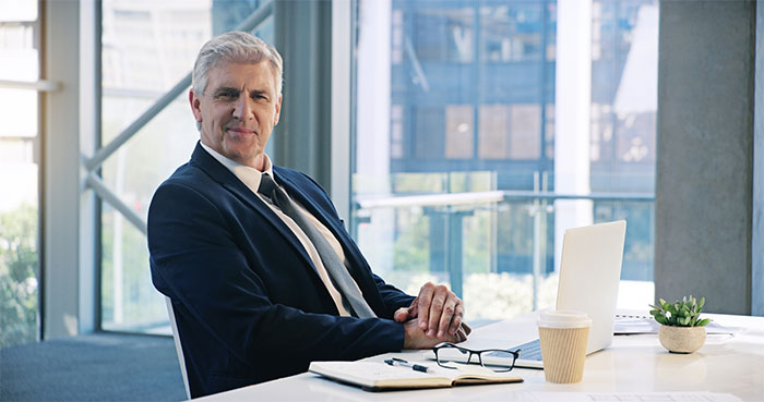 A professional in a suit sits at a desk with a laptop, symbolizing workplace insights employers keep from employees.