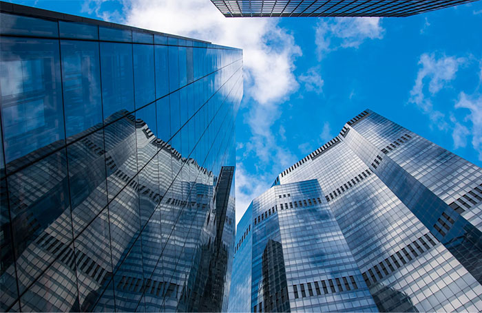 Skyscrapers reflecting a blue sky symbolize corporate secrets employers keep from employees.