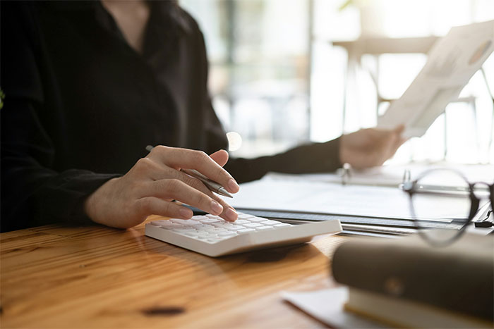 Person using calculator and reviewing documents at a desk, focusing on what employers might hide from employees.