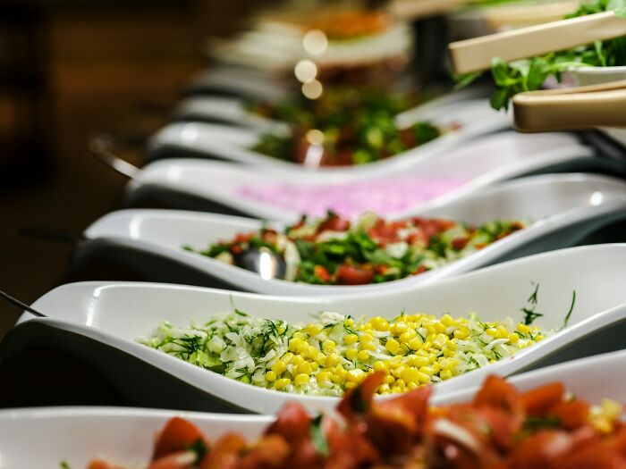 Buffet table with a variety of colorful salads, showcasing a delicious meal display.