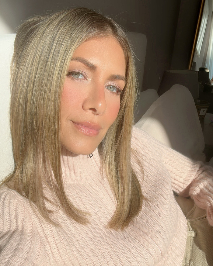 Woman with blonde hair in a pink sweater sitting, sunlight on her face, related to child safety controversy. Woman with blonde hair in a pink sweater sitting, sunlight on her face, related to child safety controversy.