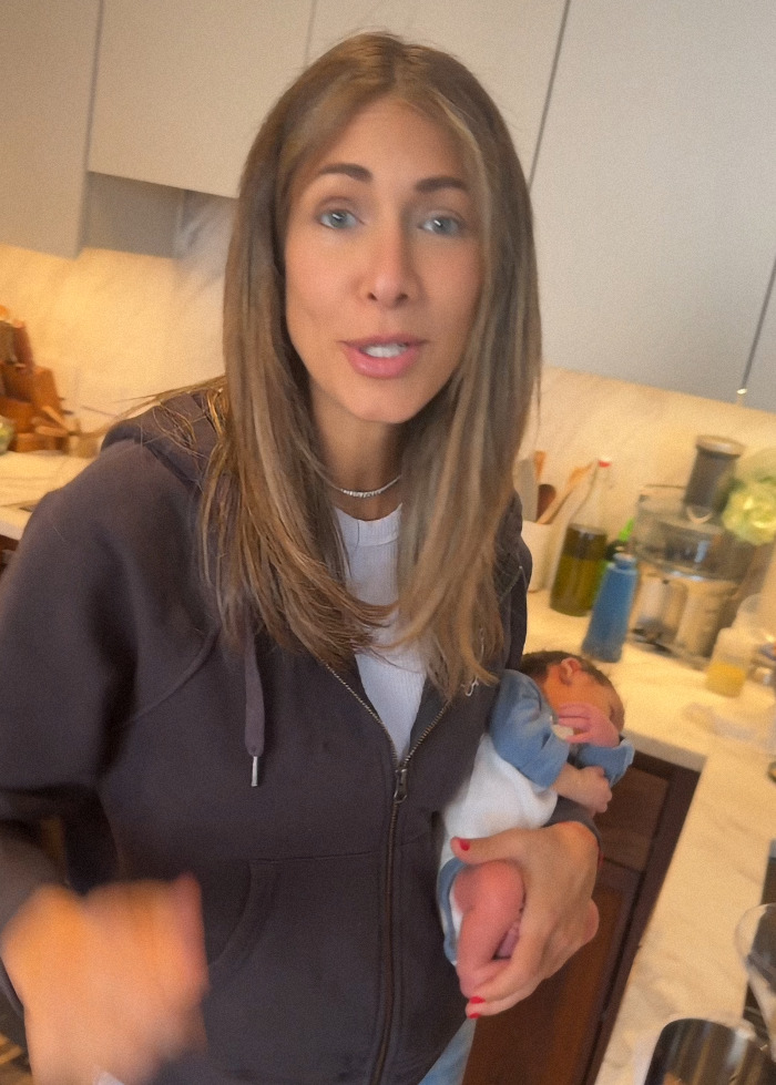 Woman holding newborn in a kitchen, preparing a martini; discussion on safer home environment for the child. Woman holding newborn in a kitchen, preparing a martini; discussion on safer home environment for the child.