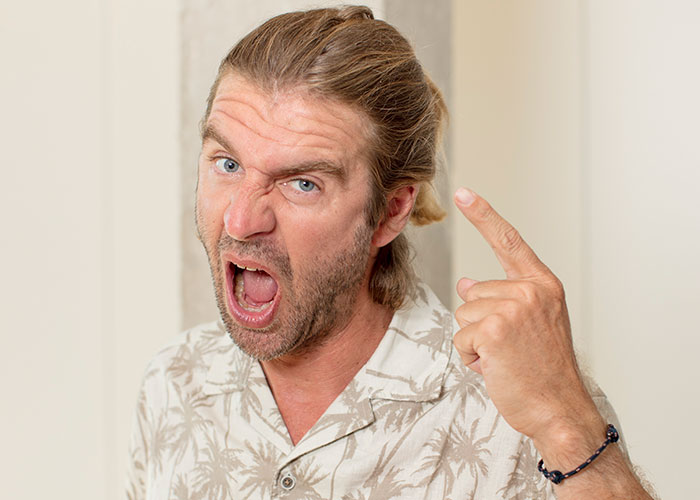 Man with a surprised expression pointing up, highlighting American traveler stereotype reactions in Europe.