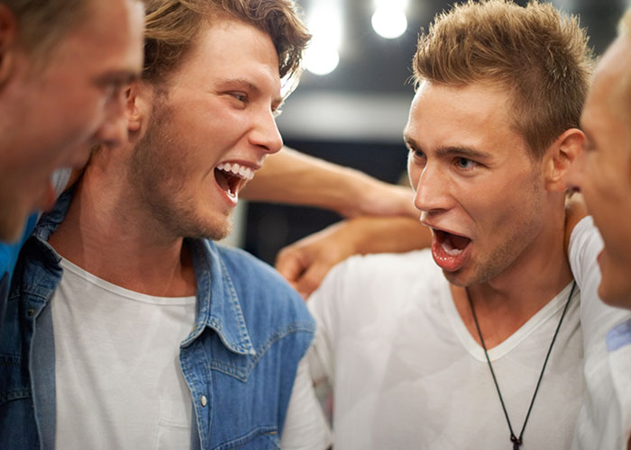 Three men laughing together, exemplifying expressions that might reveal American travelers.