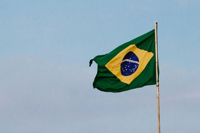 Brazilian flag waving against a clear blue sky, showcasing national pride and identity.