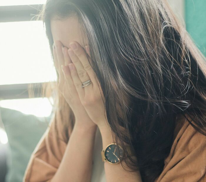 Woman covering her face in shock, possibly reacting to something disgusting happening nearby.