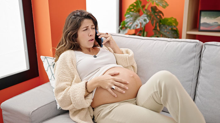 Pregnant woman on a phone call, testing her husband's loyalty in a staged labor scenario.