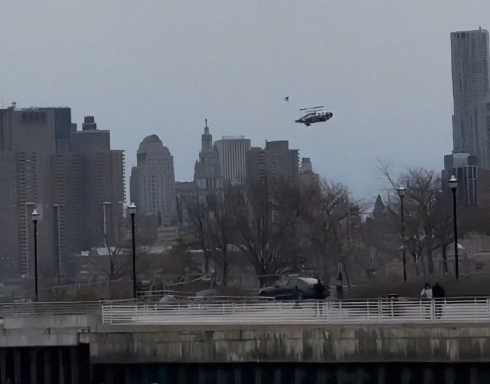 Helicopter over NYC skyline before crash, trees and buildings in the background.
