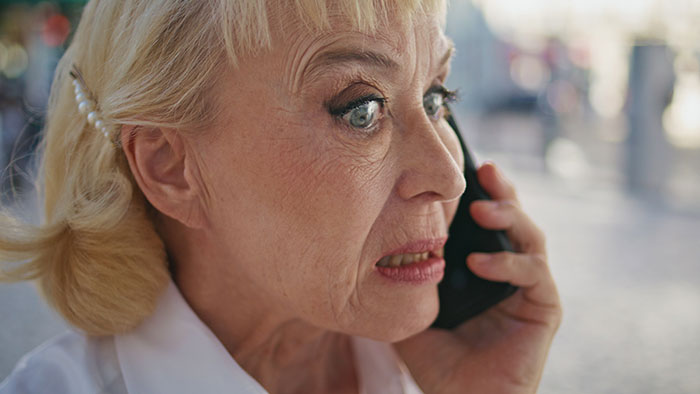 Elderly woman on phone, expressing shock, representing family drama from false CPS claims.