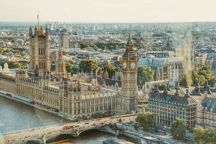 Aerial view of the Houses of Parliament and Big Ben in London, with the Thames River in the foreground.