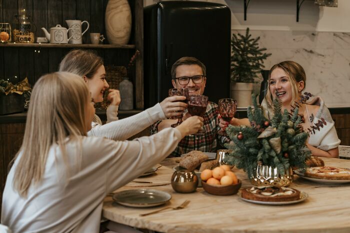 Family and friends enjoying dinner, toasting with no gifts on the table, creating a warm and festive atmosphere.