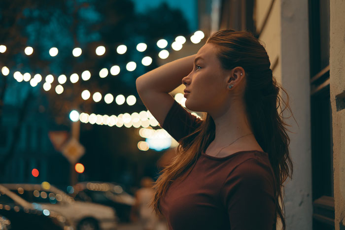 Woman standing outdoors at night, looking thoughtful; representing a wife feeling left out.