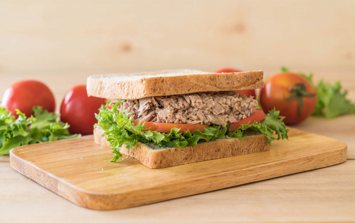 Tuna sandwich on a wooden board with lettuce and tomatoes, related to reconsidering relationships.