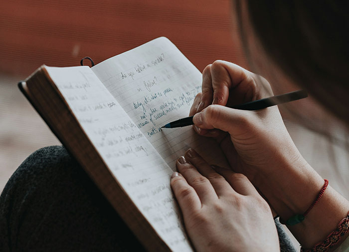 Person writing in a journal, reflecting on ending great friendships.