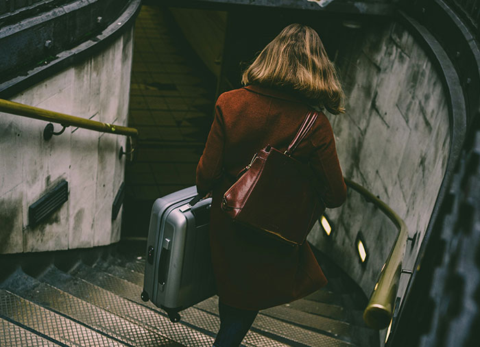 Person walking down subway stairs with luggage, reflecting on ending great friendships.