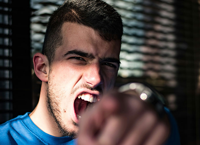 Angry man in a blue shirt pointing, illustrating the end of a friendship.