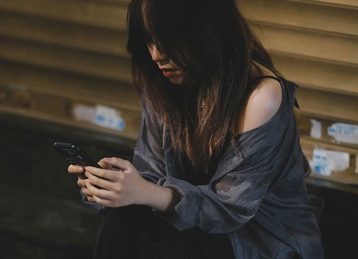 Woman sitting with a smartphone, reflecting on ending a great friendship.