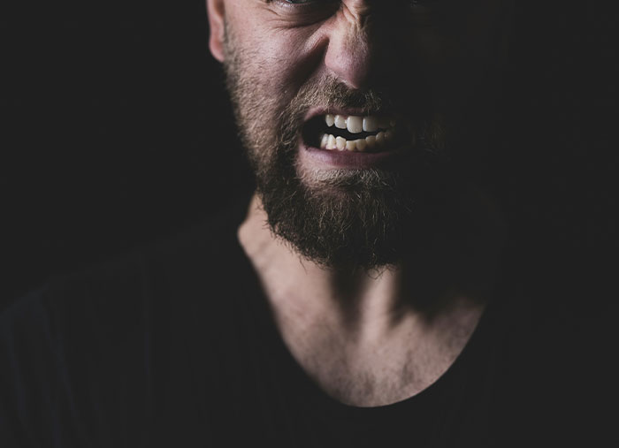 Angry man grimacing in a dark setting, reflecting emotions tied to ending friendships.