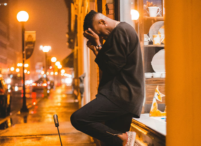 Person leaning against a building at night, looking pensive about ending friendships.